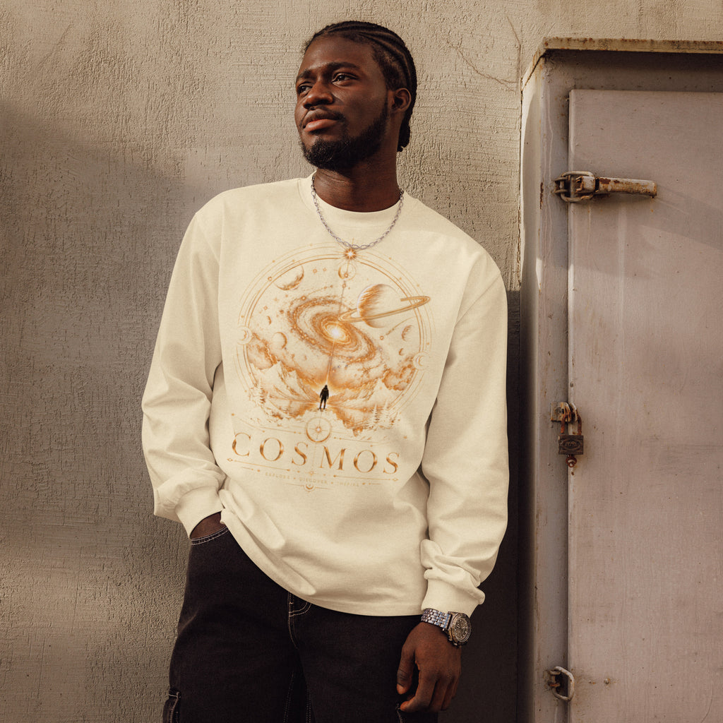 Man wearing a cream-colored Premium heavyweight long sleeve shirt - COSMOS Universe Explorer with a detailed sepia-toned cosmic design and the word COSMOS on the front.